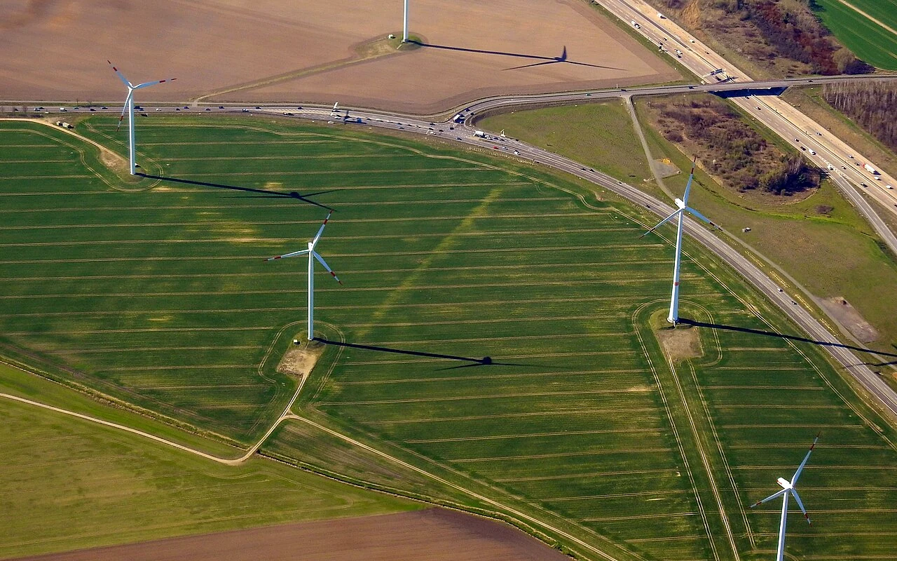 Landwirtschaftlich genutzte Flächen mit Windenergieanlagen und Verkehrswegen.